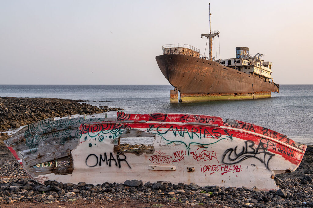 Am Strand von Lanzarote liegr ein Wrack und ein kaputtes Boot am Strand